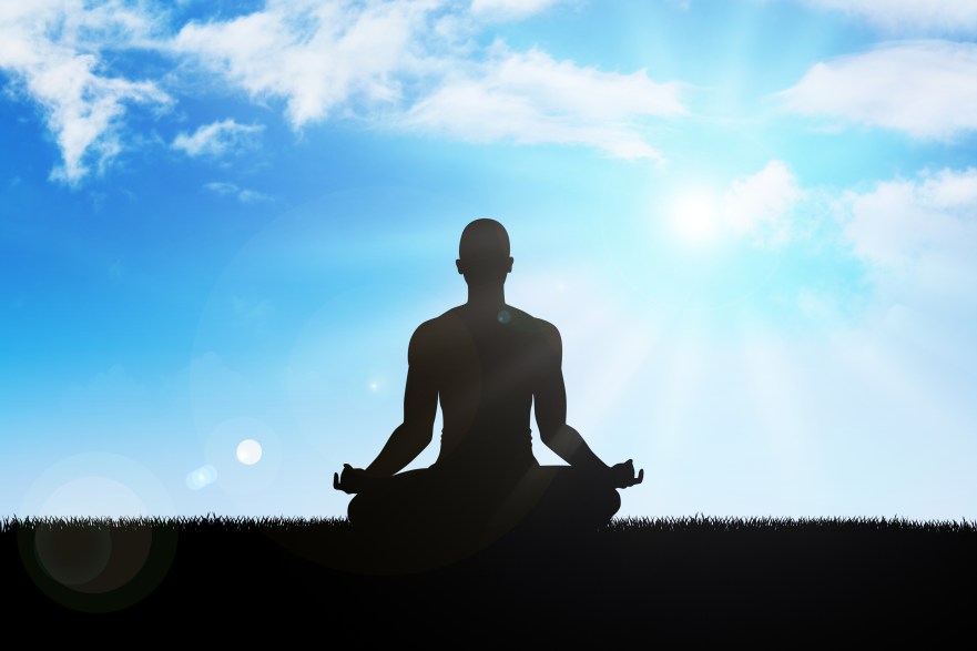 Silhouette of a man figure meditating on sky background